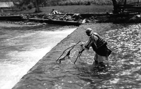 Woman fishing above a weir, Bistrita Valley, Moldavia, north-east Romania, c1920-c1945. Artist: Adolph Chevalier