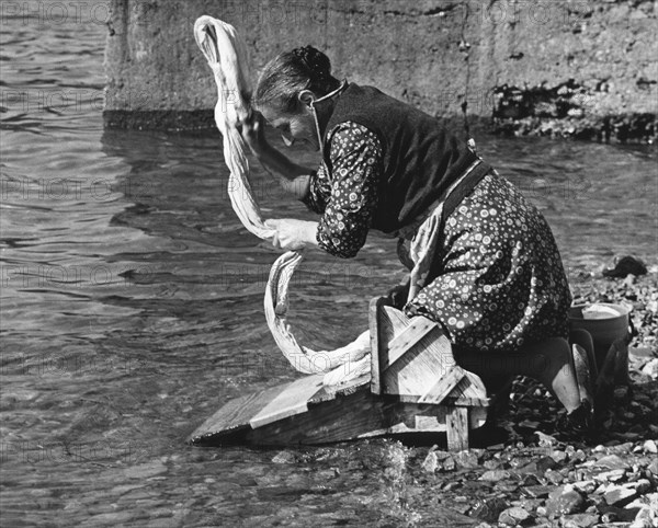Woman washing clothes in a river, Portugal, 1973.