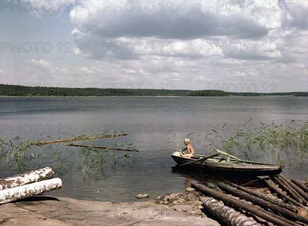 A boy fishing from a rowing boat during his summer holidays, Sweden, 1950s. Artist: Göran Algård