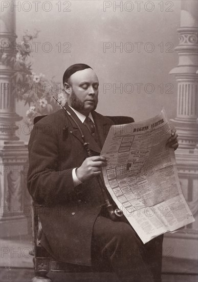 Man reading a newspaper with a long pipe in his hand, Landskrona, Sweden, 1910. Artist: Unknown