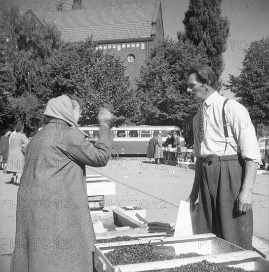 A women buying lingonberries in the market square, Landskrona, Sweden, 1952. Artist: Unknown