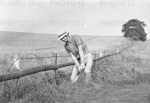 Golfer playing from a bad lie in deep rough, nearly out of bounds, Sweden, 1969. Artist: Unknown