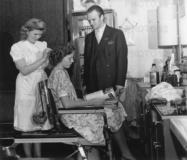 A girl passing the test to qualify as a hairdresser before a male inspector, Sweden, c1940-1959. Artist: Unknown