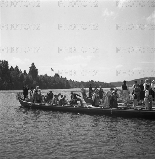 People arrive in long boats, called church boats, for the Midsummer celebrations, Sweden, 1941. Artist: Torkel Lindeberg