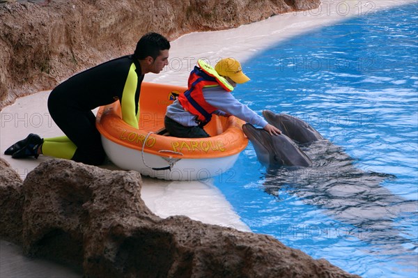 Child petting a dolphin, Loro Parque, Tenerife, Canary Islands, 2007.