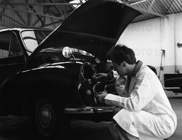 Auto electrician changing a light bulb on a Morris Minor, Nottingham, Nottinghamshire, 1961.  Artist: Michael Walters