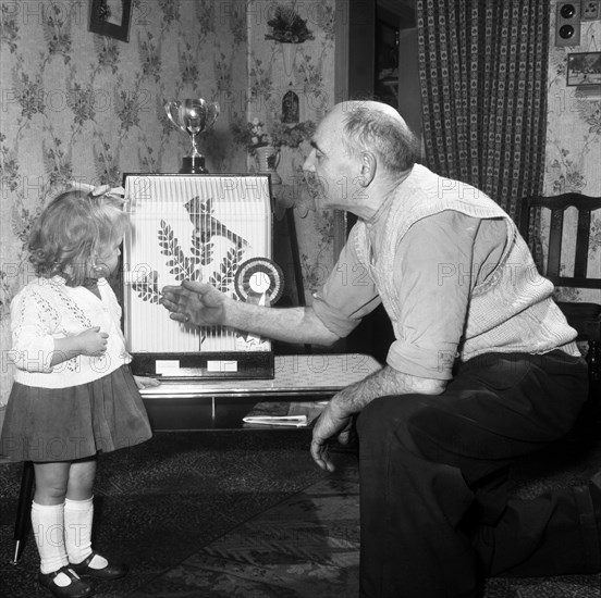 Grandfather and child with a prize winning caged bird, Horden, County Durham, 1963. Artist: Michael Walters