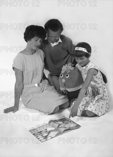 Family group looking at a magazine, 1963. Artist: Michael Walters