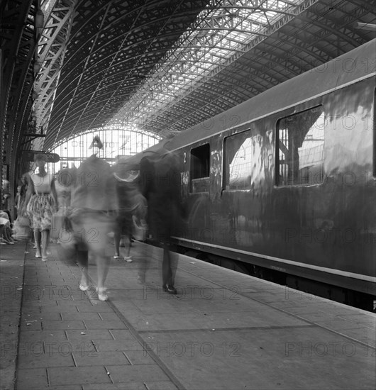 Travellers walking along a platform at Centraal Station, Amsterdam, Netherlands, 1963. Artist: Michael Walters