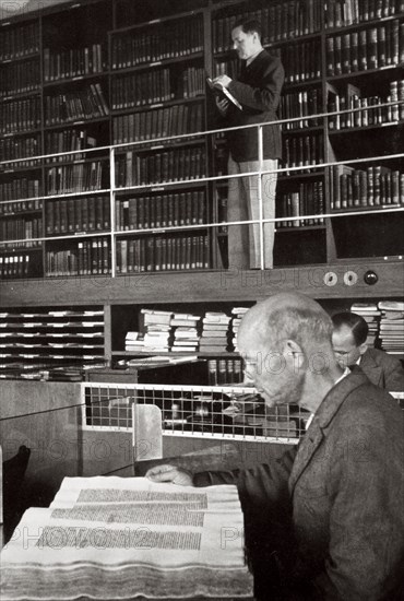 A labourer reads a book in a library, Germany, 1936. Artist: Unknown