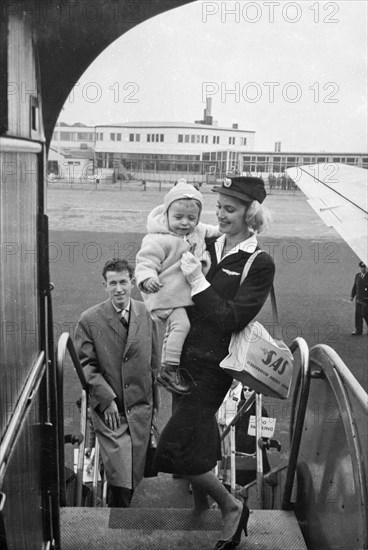SAS stewardess carrying a baby onto a plane, Bulltofta airport, Malmö, Sweden, 1950. Artist: Torkel Lindeberg
