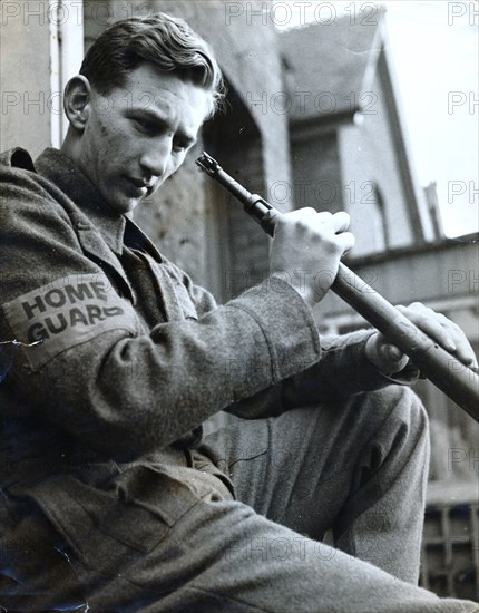 British Home Guard soldier cleaning his rifle, World War II, c1940-c1944. Artist: Unknown