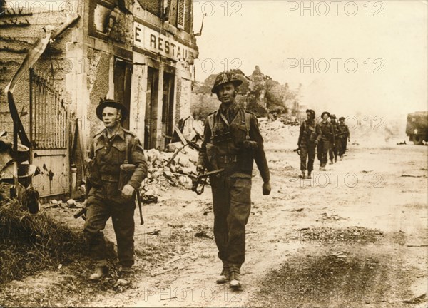 British troops walk through the village of Douet, after the fall of Bayeux, June 1944. Artist: Unknown