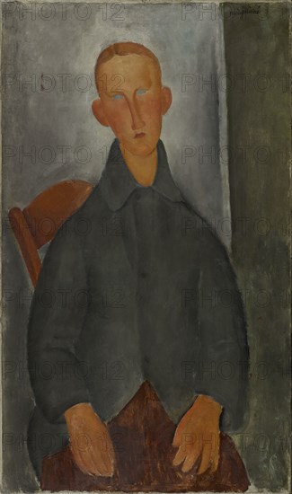 Seated boy with red hair and grey jacket.