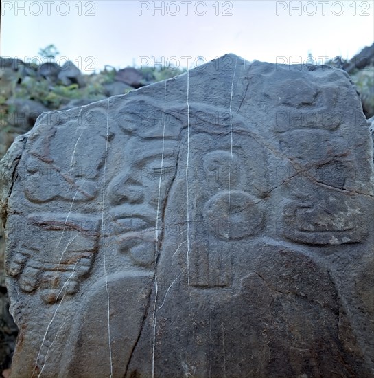 Detail of a sculptural relief on a rock representing a man with a large earring, at his left the ?