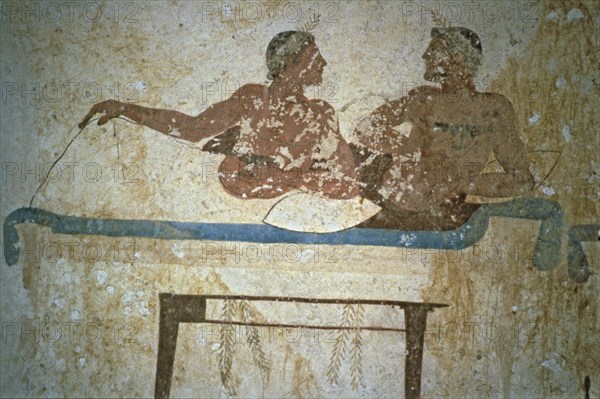 Fresco depicting two men lying on a bed in the Tuffatore tomb at Paestum.