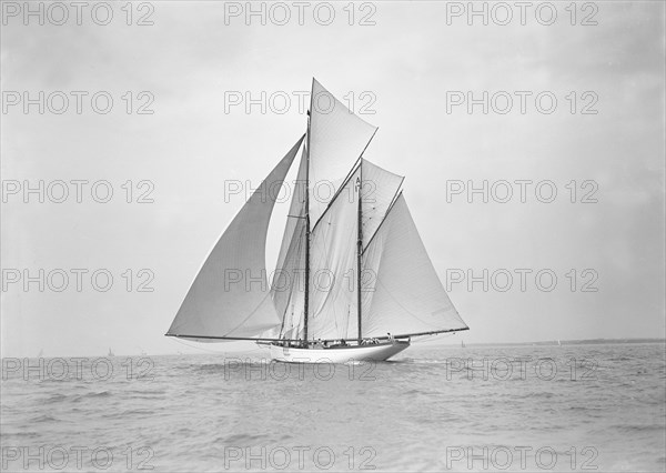 The 118 foot racing yacht 'Cariad' sailing with spinnaker, 1911. Creator: Kirk & Sons of Cowes.