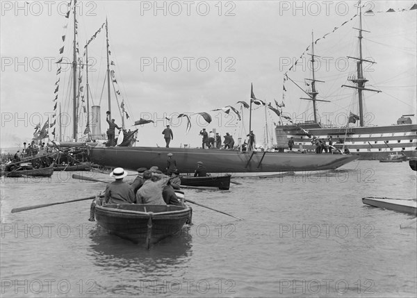 The launch of 'Shamrock IV' with H.M.S. Victory in the background, May 1914. Creator: Kirk & Sons of Cowes.