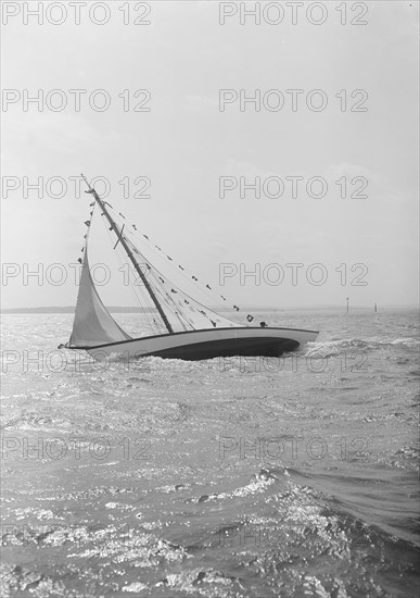 The 7 Metre 'Ginerva' (K7) under sail with prize flags, 1912. Creator: Kirk & Sons of Cowes.