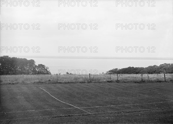 View of a tennis court and the sea, c1935. Creator: Kirk & Sons of Cowes.