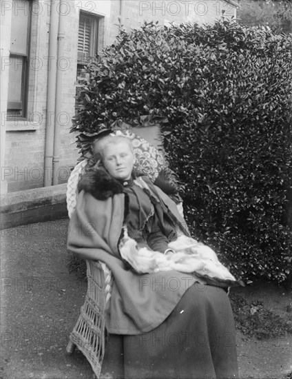 Woman sitting in a chair in a garden, c1900. Creator: Kirk & Sons of Cowes.