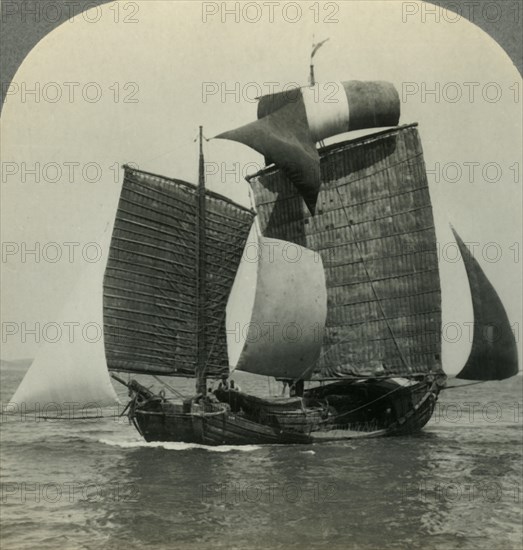 'Picturesque Chinese Junk under Full Sail on the Yellow Sea, Coast of Manchukuo in Distance', c1930s Creator: Unknown.