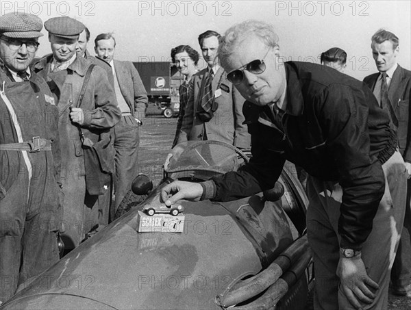 Mike Hawthorn admiring a toy model Ferrari on his racing Ferrari. Creator: Unknown.