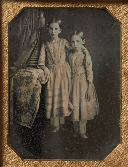 Two Identically Dressed Young Girls Standing Next to a Table, 1840s.