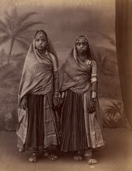 Two Hindu Women in Elaborate Jewelry, Before Studio Backdrop with Palm Trees, 1860s-70s.