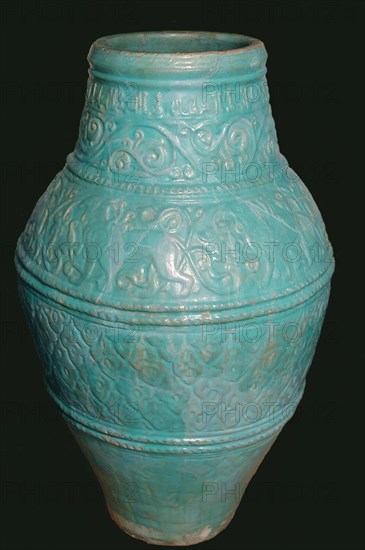 Large Turquoise Jar, Iran, 12th-13th century. Motifs typical of the Seljuq period including winged griffins and arabesque design. with inscriptions of good wishes  in small kufic script.