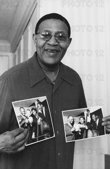 Bob Cranshaw, Swinging Jazz Party, Blackpool, 2005; backstage holding photos of the Junior Mance Trio taken by Brian Foskett.