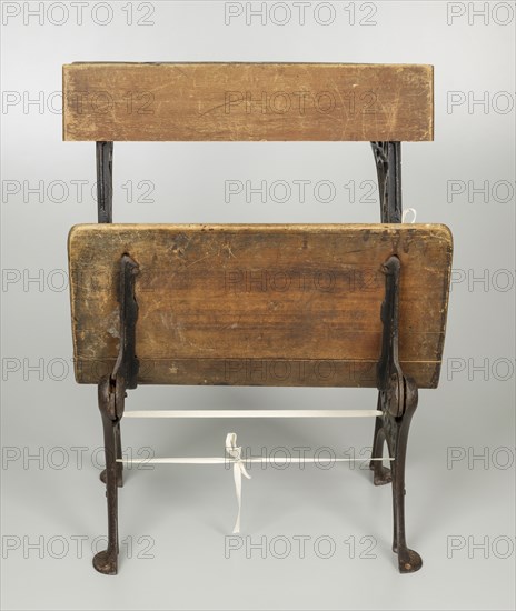 Wood and iron school desk with a foldable seat.