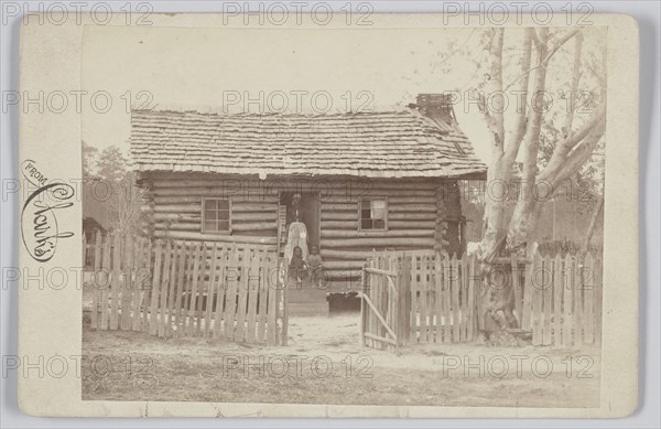 Albumen print of a woman and two children in front of a log house in Georgia, 1880s. Creator: H. S. Clark.