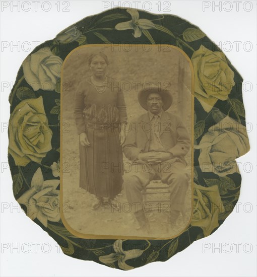 Photographic portrait of a man and woman on floral paper backing, early 20th century. Creator: Unknown.