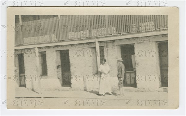 Photograph of a man and woman standing on a sidewalk, early 20th century. Creator: Unknown.