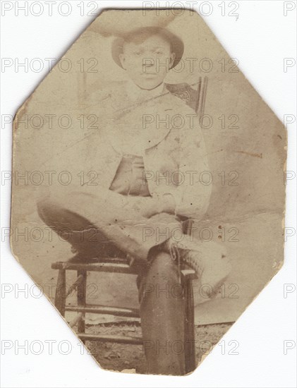 Photographic print of a man in suit sitting on a chair with right leg crossed, late 19th-early 20th  Creator: Unknown.
