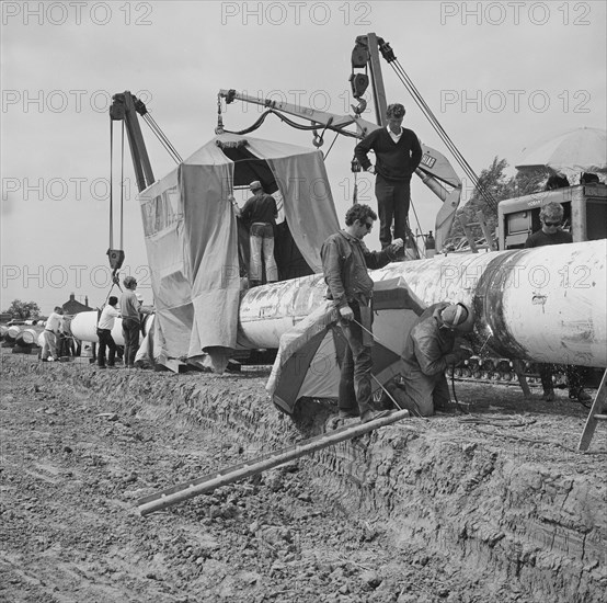 A team of men working on the lining up operation of the Fens gas pipeline, Norfolk, 24/07/1967. Creator: John Laing plc.