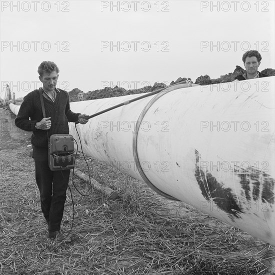 A worker walking along a section of the Fens gas pipeline, Norfolk, 24/07/1967. Creator: John Laing plc.