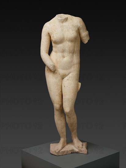 Statue of the Aphrodite of Knidos, 2nd century. White and beige stone statue of a female nude standing in contrapposto position, with weight on the right leg. The head of the statue is missing. The left arm has been broken off just past the shoulder, and the left hand is also absent.