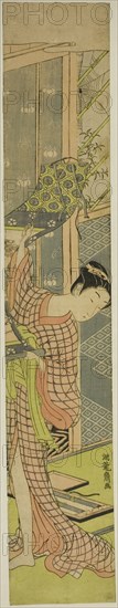 Young Woman Hanging a Painting, c. 1771. Creator: Isoda Koryusai.