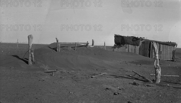 Fence corner and outbuilding being buried by dust, Mills, New Mexico, 1935. Creator: Dorothea Lange.