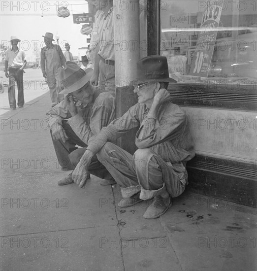 Drought farmers line the shady side of the main street of the town, Sallisaw, Oklahoma, 1936. Creator: Dorothea Lange.