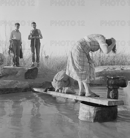 Oklahoma migratory workers washing in a hot spring in the desert, Imperial Valley, California, 1937. Creator: Dorothea Lange.