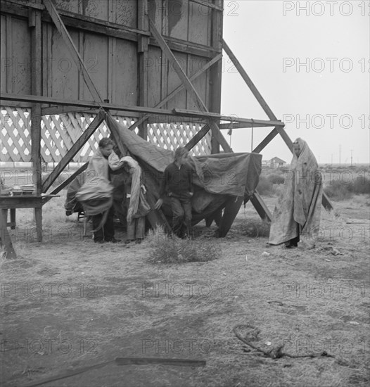 One of three families camped behind a billboard on U.S. 99, Kern County, California, 1938. Creator: Dorothea Lange.