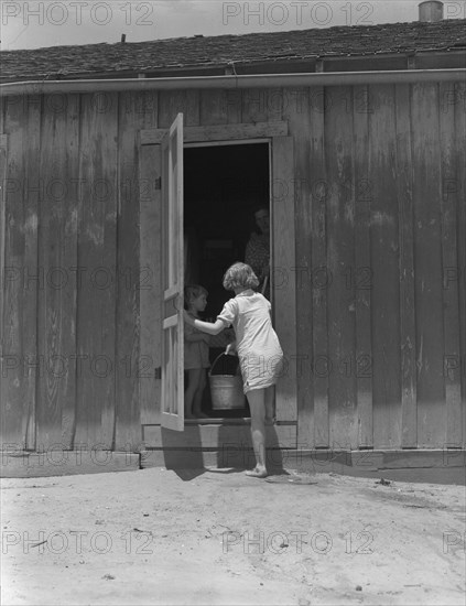 Child of Texas sharecropper carrying water, 1937. Creator: Dorothea Lange.