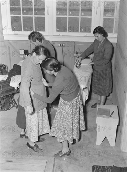 Camper receives help in fitting a coat from WPA sewing instructor, FSA, California, 1938. Creator: Dorothea Lange.