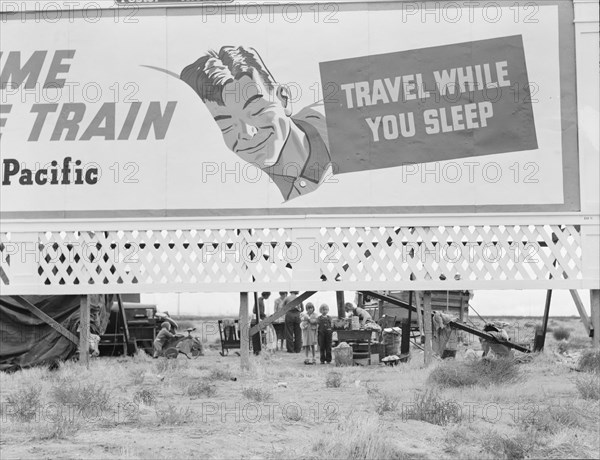 Billboard along U.S. 99 behind which three destitute families..., Kern County, California, 1938. Creator: Dorothea Lange.