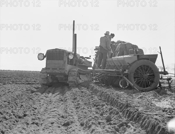 Loading bins of potato planter with fertilizer and seed..., Kern County, California, 1939. Creator: Dorothea Lange.