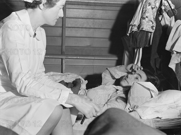 Nurse attending sick migrant woman, FSA camp, Farmersville, Tulare County, California, 1939. Creator: Dorothea Lange.