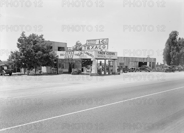 Small independent gas stations litter the highway, near Kingsburg, California, 1939. Creator: Dorothea Lange.